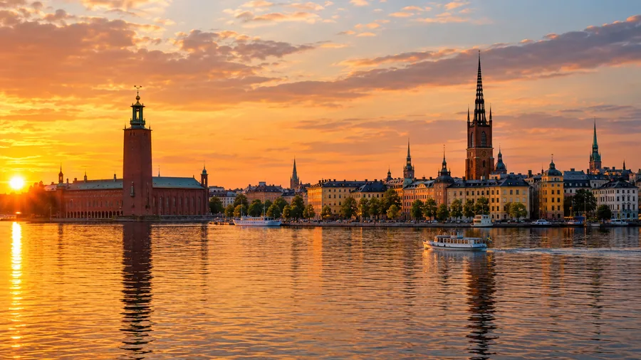 Der Turm des Stadshuset und der Kirchturm von Riddarholmen über dem ruhigen Mälaren im goldenen Abendlicht